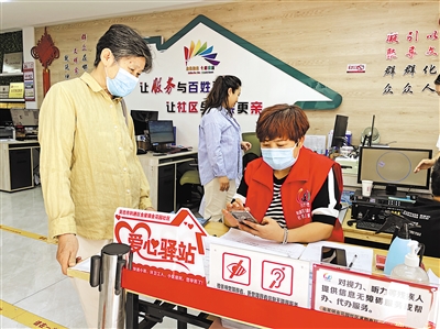 8月31日，社區(qū)工作人員幫助老年居民在手機(jī)上辦理業(yè)務(wù)。      本報(bào)記者 毛雪皎 攝